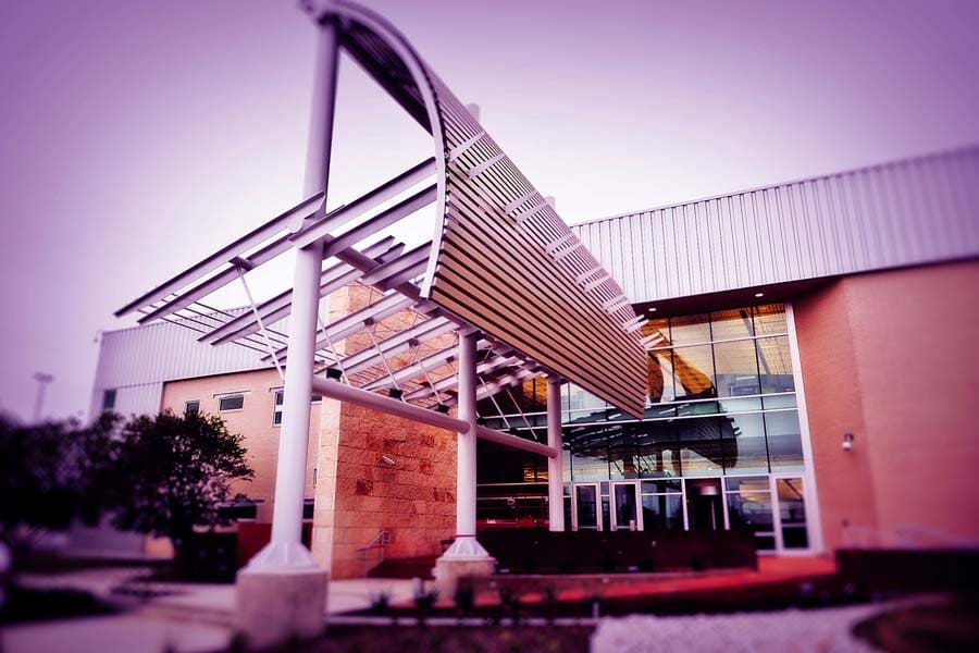 Wide exterior shot of the Rackspace building featuring a large metal entrance canopy and modern curtainwall facade, illuminated with atmospheric lighting