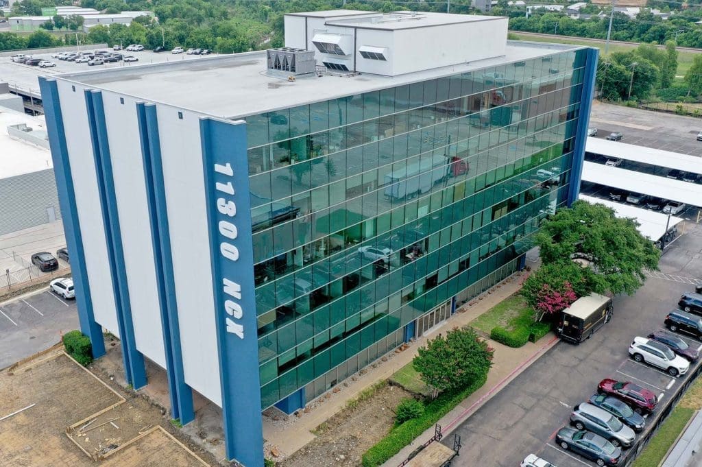 Aerial photograph of the completed Royal Central Tower renovation, featuring the new sleek glass curtainwall exterior, modernized entrance, and '11300 NCX' signage designed and consulted by CES