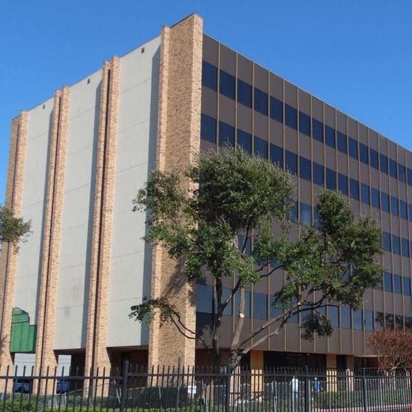 Exterior view of the original Royal Central Tower featuring a dated brown and beige stucco facade with dark ribbon windows, prior to the tornado damage and subsequent renovation