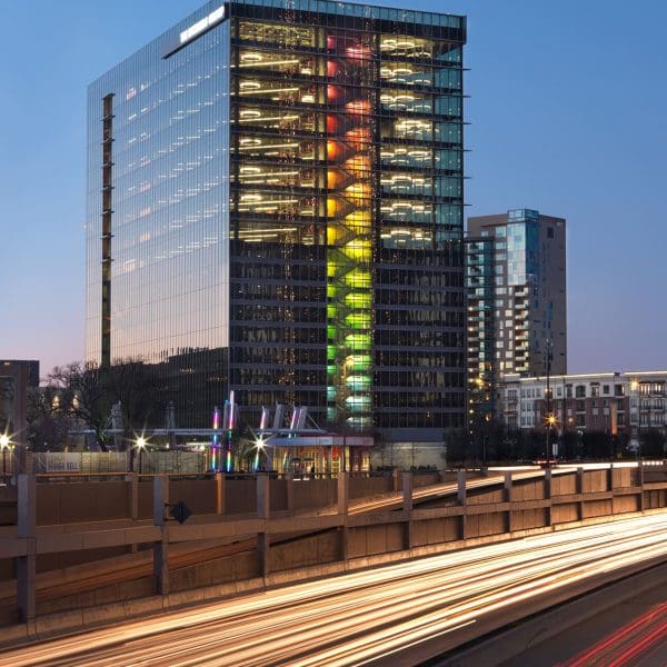 Dusk view of the office building from the highway, highlighting the illuminated glass stairwell and the cantilevered curtainwall 'wing wall' detailed by CES