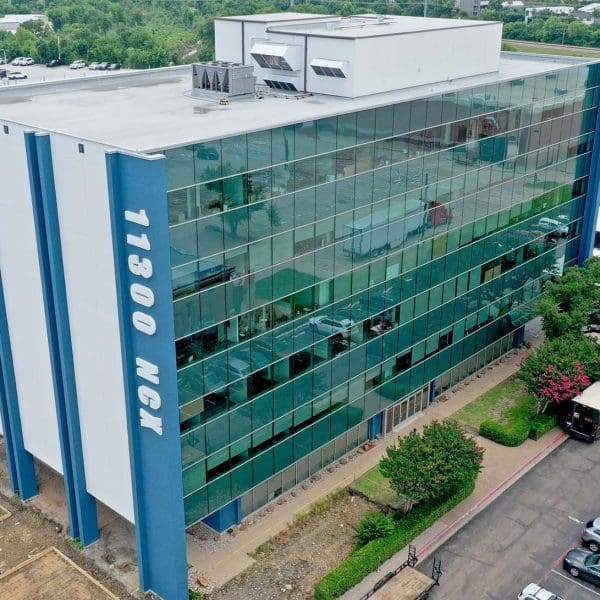Aerial photograph of the completed Royal Central Tower renovation, featuring the new sleek glass curtainwall exterior, modernized entrance, and '11300 NCX' signage designed and consulted by CES